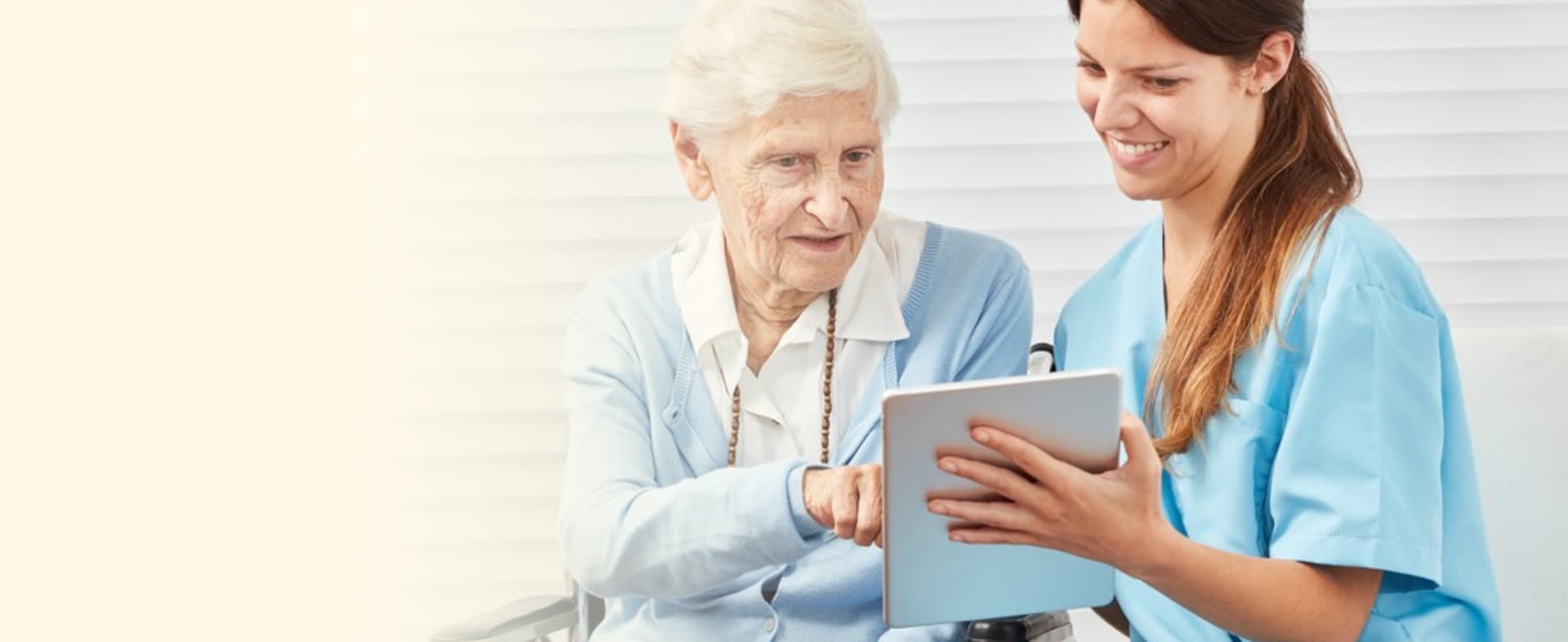 caregiver teaching a senior woman using tablet
