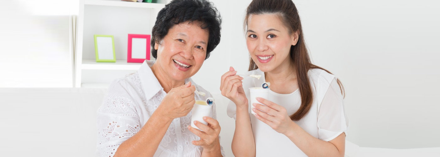 caregiver and a senior woman eating yogurt